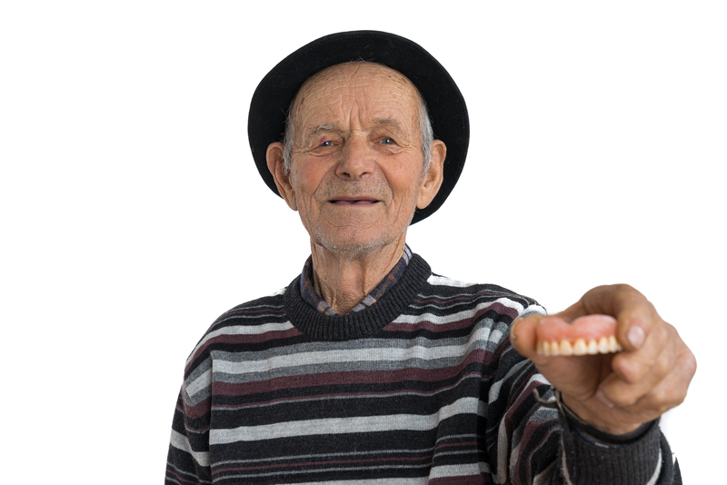 toothless man holding his dentures